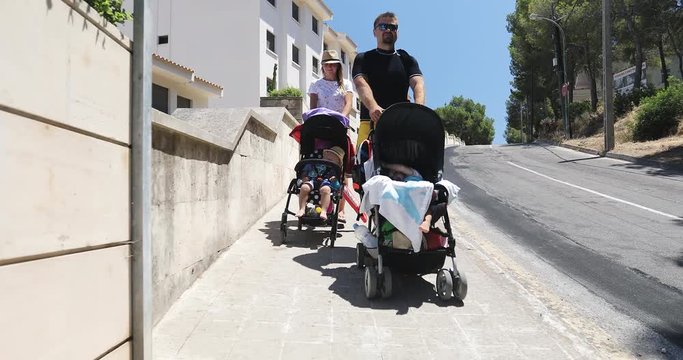 A man and a woman carry prams with children on vacation in the summer.
