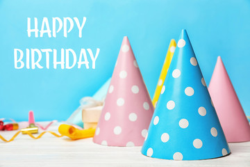 Birthday party caps on table against color background