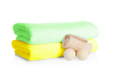 Stack of clean soft towels, bath bombs and sponge on white background