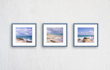 Frames with sea view pictures, three  wooden frameworks isolated on white textured wall