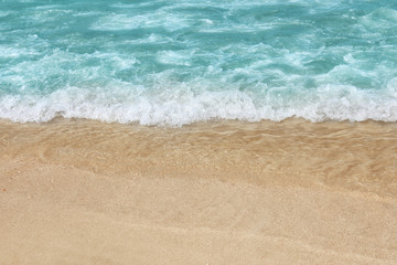 Fototapeta na wymiar Beautiful blue wave with sea foam on sandy beach