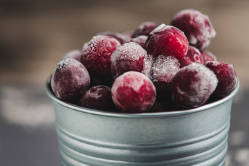 frozen cherry plum in a bucket on a light grey background
