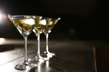 Glasses of martini cocktail with olives on bar counter. Space for text