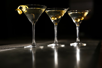 Glasses of martini cocktail with olives and lemon peel on bar counter. Space for text