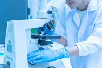 Young asian scientist looking through a microscope in a laboratory.Thailand people doing some research.