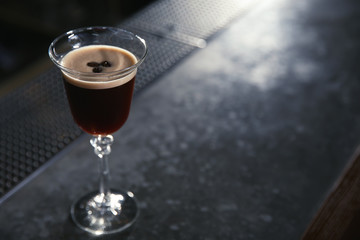 Glass of martini espresso cocktail on bar counter. Space for text