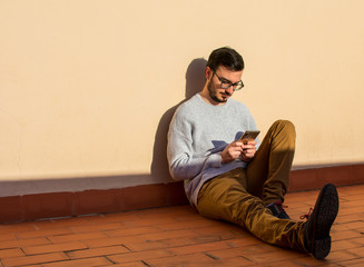 Fototapeta premium Man using mobile phone on rooftop. Talking in a balcony