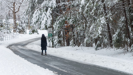 Asian woman walking down snow covered street