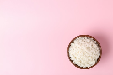 Bowl of boiled rice on color background, top view with space for text