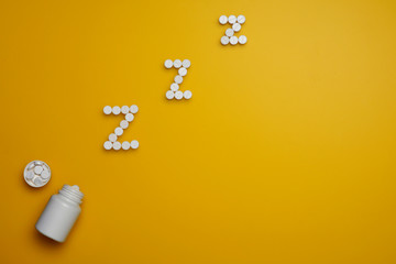 White round somnifacient pills on yellow background.