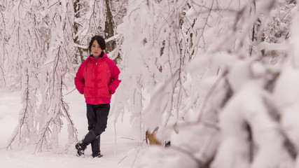 Young Asian girl surrounded by snow covered trees