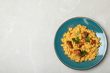 Plate of delicious rice pilaf on light background, top view with space for text