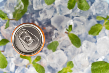 Fizzy drink in a aluminium tin can on the background of ice cubes and fresh mint leaves. Top view.