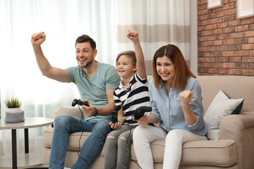 Happy family playing video games on sofa in living room