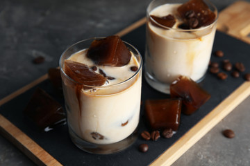 Glasses of milk with coffee ice cubes on grey table