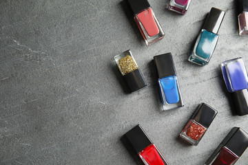 Bottles of nail polish on grey background, top view with space for text