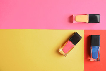 Bottles of nail polish on color background, top view with space for text
