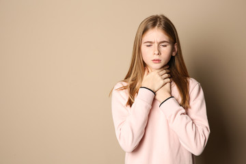 Teenage girl suffering from cough on color background. Space for text