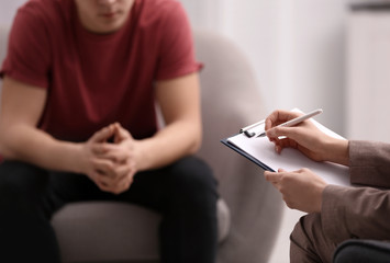 Psychotherapist working with young man in office, closeup