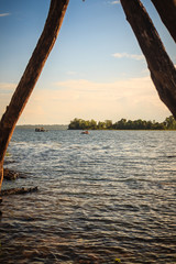Fototapeta premium Peaceful blue lake with green grass and blue sky background. Beautiful blue sky and clouds over the reservoir. Rafting activity in the still water lake under blue sky and cloudy day.