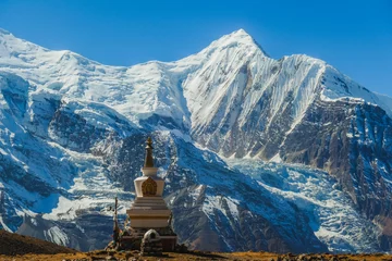 Photo sur Plexiglas Manaslu Un stupa avec Annapurna Chain en toile de fond, Annapurna Circuit Trek, Himalaya, Népal. Hautes montagnes couvertes de neige. La terre devant le stupa est stérile et sèche. Un drapeau de prière à côté.