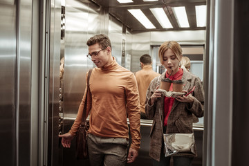 Wife sipping cappuccino while taking elevator with her man