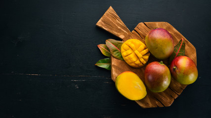 Mango with leaves on a black wooden background. Tropical Fruits. Top view. free space for your text.