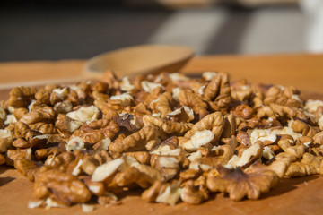 Closeup of Peeled Walnuts pile. Walnuts Background. Walnuts on wooden cutting board with wooden spoon. Selective focus