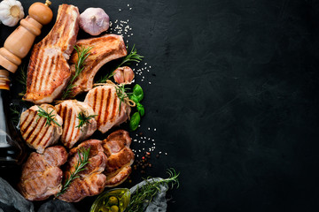 Grilled Meat. Seth meat. Grill, barbecue. On a black stone background. Top view. Free copy space.