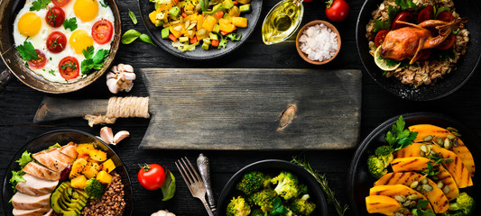 Assortment of food. Salad, avocado, quail, mushrooms, pumpkin. On a black background. Top view. Free space for your text.
