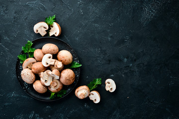 Mushrooms in a plate. Champignons on the old background. Top view. Free copy space.
