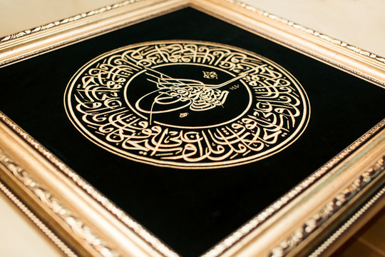 Tughra Ottoman Turkish muslim signature. Luxury arabic ligature embroidered with golden silk threads on black velvet background, seal or signature. Bismillah tugra Islamic framed calligraphy