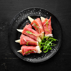Prosciutto with pear and arugula. Cold snacks. Top view. Free space for your text.