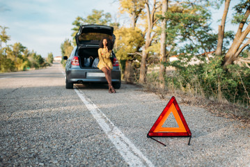 Woman with broken car and triangle