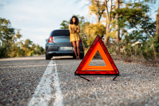 Woman with broken car and triangle