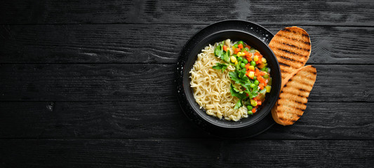 Asian soup with noodles and vegetables in a bowl, with toast bread. Dietary food. Top view. Free copy space.