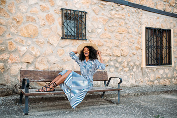 Woman sitting on a bench near a stone house