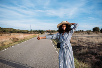 Happy black woman hitchhiking with thumbs up