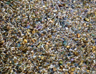 A background of colorful rocks under refracting light in water