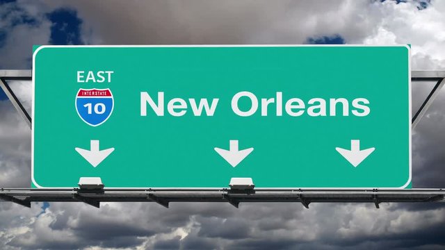 New Orleans interstate route 10 overhead freeway directional arrow sign with time lapse clouds.