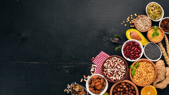 Various superfoods. Dried fruits, nuts, beans, fruits and vegetables. On a black wooden background. Top view. Free copy space. © Yaruniv-Studio