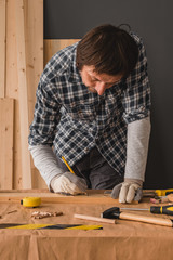 Carpenter sketching pine wood plank for cutting in workshop