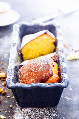 Yogurt plumcake made with almond and gluten free, with colored easter egg, shot from a top viewpoint over a rusty wooden black background,flare added