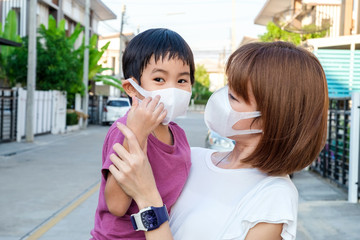 Asian young mother wearing protective PM2.5 mask for her son at outdoor