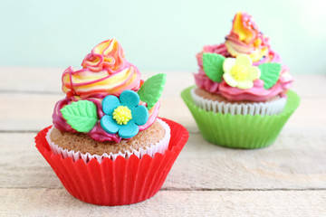 Colorful cupcakes with sugar flowers and vanilla cream close up