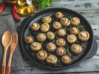 Fried, baked mushrooms in frying pan on wooden table