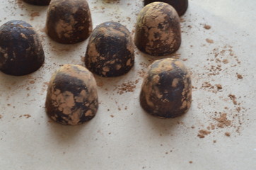 Chocolate candy truffle with chocolate pieces and flying cocoa powder on a dark background