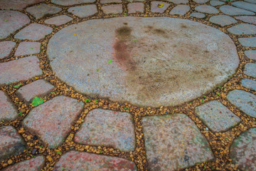 Vintage grungy gray pavement of cobblestones in a circle patterned background. Pavement of granite...