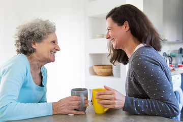 Cheerful senior mother and adult daughter sharing good news