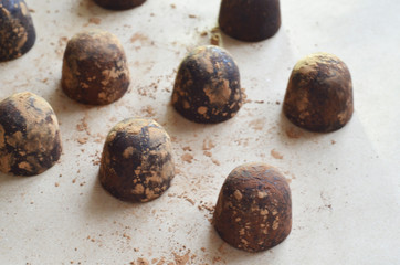 Chocolate candy truffle with chocolate pieces and flying cocoa powder on a dark background